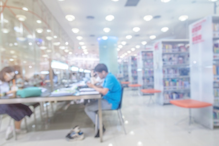 Abstract Blur image of library interior background with people study on workink desk