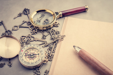 Magnifying Glass wuth pencil and blank notebook on grey leather travel concept