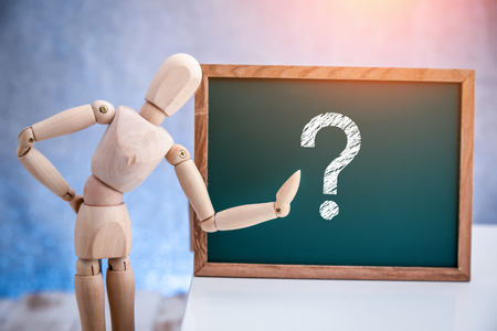 Wooden concept of mannequin in pose with wood frame and question mark symbo;の写真素材