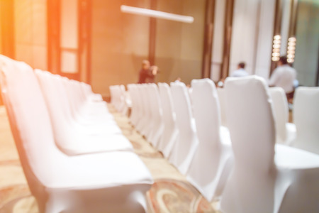 Blurred background of empty chairs with people in convention or meeting roomの写真素材