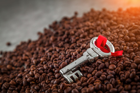 Coffee beans texture background. Closeup of fresh roasted bag of dark roast coffee beans pattern and silver key, useful for text copy space, element detail or advertisement background.の写真素材