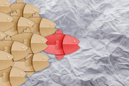 business leader success concept with red and brown fish paper shape on crumpled paper backgroundの写真素材