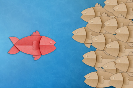 business leader success concept with red and brown fish paper shape on blue backgroundの写真素材
