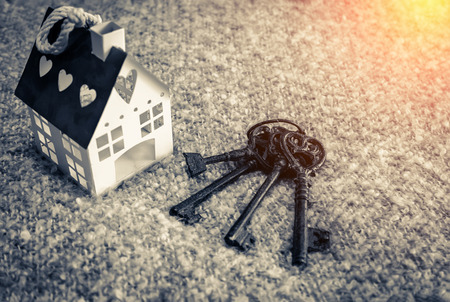home sweet home house model on fabric  beige color and old rustic metal keys with light flare effect
