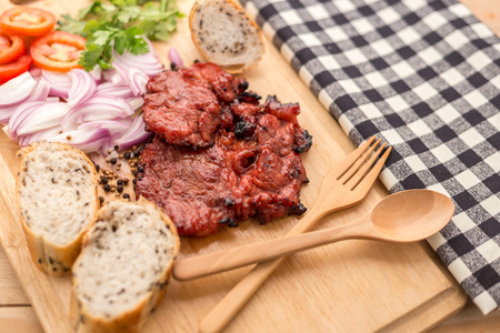 Grilled pork chops in sweet honey glaze, served in grill iron skillet with fresh thyme, rye bread and cherry tomatoes, close up. Selective focusの写真素材