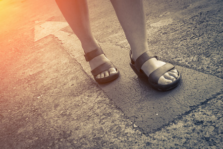 yellow direction street sign with walk of woman in leather shoe business leader conceptの写真素材