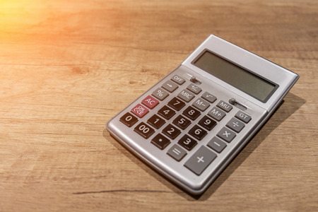 Press the button on the calculator with a wooden floor in the background with free copyspaceの写真素材