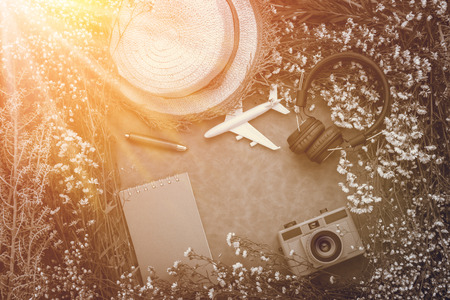 Summer travel object composition of headphone toy camera flowers frame with blank notebook on the wooden table in summer seasonの写真素材