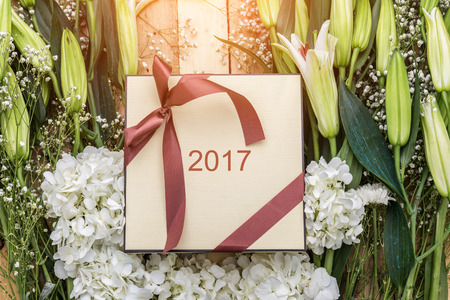 Background with white flower frame and gift box with red nice ribbon on old grey boards. Place for...