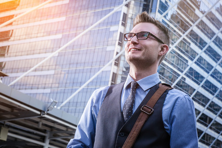 Low angle shot of a corporate executive walking along a modern corridor smiling with success vision with len flare effectの写真素材