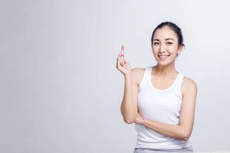 Beautiful asian girl applying lipstick studio shoot with white backgroundの写真素材
