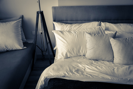 Bed maid-up with clean white pillows and bed sheets in beauty room. Close-up. Lens flair in sunlight.の写真素材