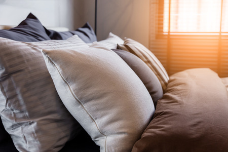 Bed maid-up with clean white pillows and bed sheets in beauty room. Close-up. Lens flair in sunlight.の写真素材