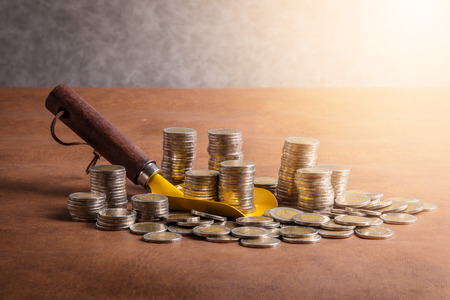 business finance ideas concept with money coins and shovel on leather background with free copyspace for your idea textの写真素材