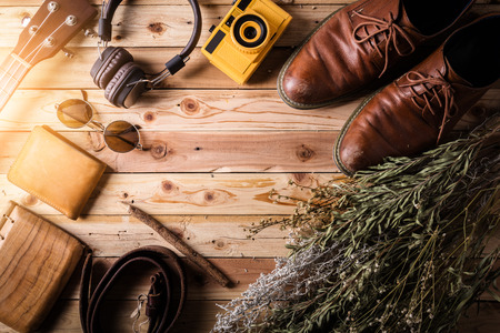 travel stuff concept with jeans leather wear headphone and  toy camera on old vintage wooden floor and flower with free copyspace for your textの写真素材