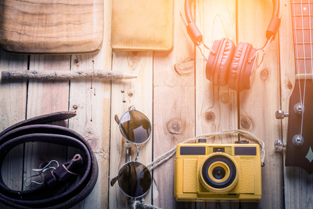 travel stuff concept with jeans leather wear headphone and  toy camera on old vintage wooden floor and flower with free copyspace for your textの写真素材