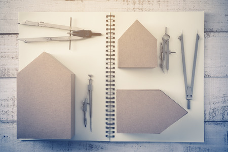 house deisgn concept with house paper cardboard and drawing tool on notebook and vintage wood backgroundの写真素材