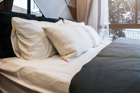 Bed maid-up with clean white pillows and bed sheets in beauty bedroom.