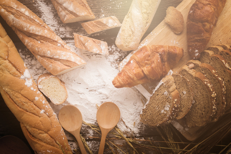 Fresh baked bread on dark wood table with copy space background  still life composition with wheat...