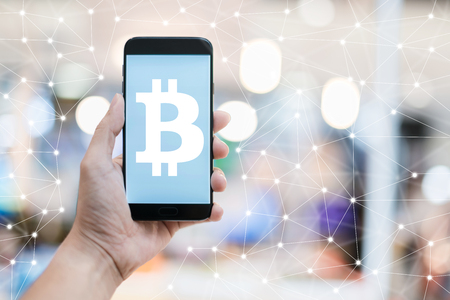 business CRYPTO CURRENCY BITCOIN  ideas concept with hand hold white blank screen smartphone with blur bokeh mall backgroundの写真素材