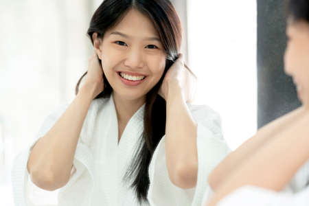 beautiful asian woman bathing dress hair brush and dress up with reflecting mirror bathroom...