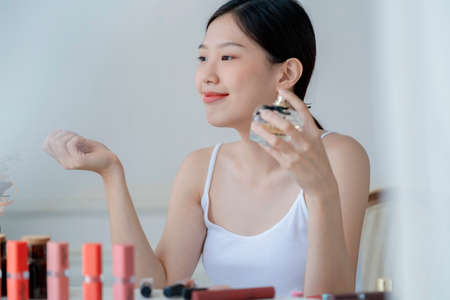 beautiful asian woman white tshirt smile with happiness hand hold blush on and makeup cosmetic items in bedroom with healthy  face skincare conceptの写真素材