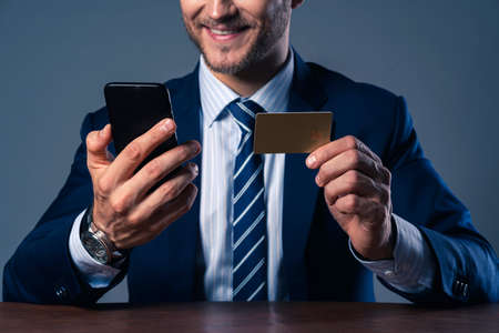 successful  caucasian businessman suit beard hand hold smartphone and credit card with happiness...