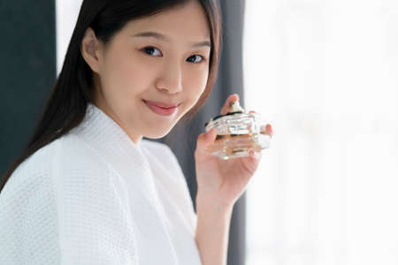 beautiful asian woman in white bathing dress enjoy good smell of new perfume bathroom backgroundの写真素材