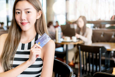 Young attractive beautiful asian woman big smile using credit card for shopping online in coffee...