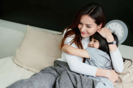 beautiful single mom and daughter girl kid hug together with love and care on bed morning happiness...