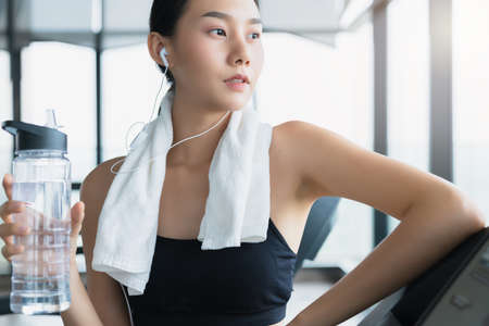 Exhausted asian female girl standing on the treadmill in the gym relax and cooldown healthy ideas conceptの写真素材