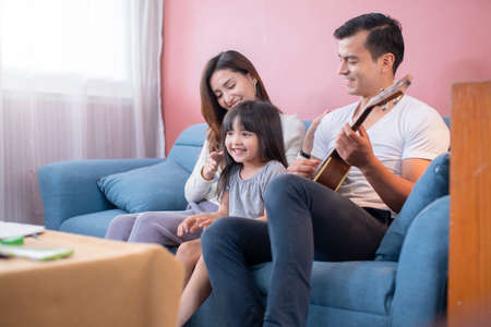 happiness family enjoy weekend together with sind and ukulele in family living room home conceptの写真素材