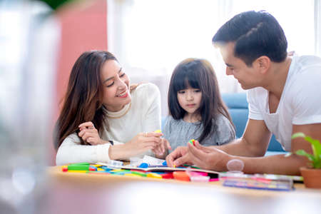 happiness lovely father mother teach homework for little preety daughter in living room family conceptの写真素材