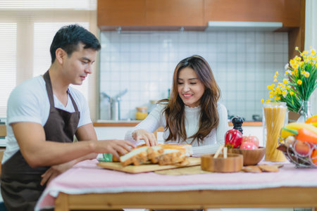 sweet asian couple happiness moment together preparing breakfast in kitchen house conceptの写真素材