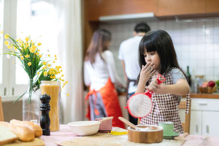 cute daughter learn to cook with her parent in kitchenの写真素材