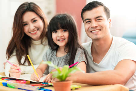 cute black hair child female daughter homework and laugh together with parent in living room house conceptの写真素材