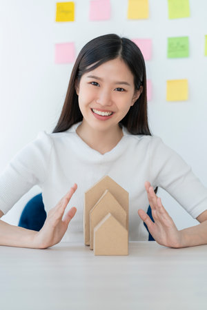 business home asset ideas concept with beautiful smart asian woman hand protect house model with happiness and confidentの写真素材