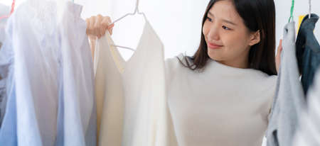 pretty happiness asian woman shopping with fun chooing cloths dress in store white room backgroundの写真素材