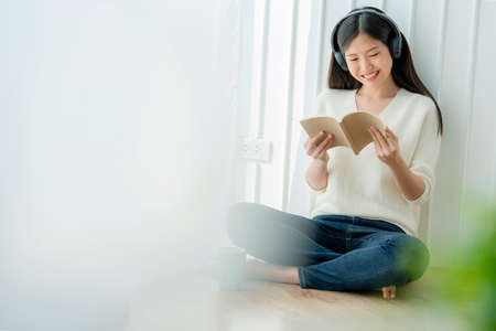 happiness and peaceful asian woman enjoy melody and book weekend house background