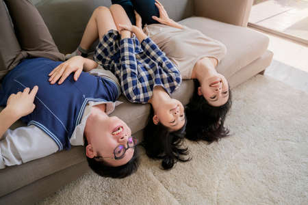 happiness asian family mom dad daughter play fun together on brown sofa with laught and joyful