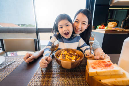 happiness asian mom and daughter enjoy cereal breakfast time healthy food concept dinning room backgroundの写真素材