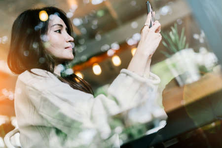 beautiful asian woman enjoy hot drink morninig time near window in cafe shop lifestyle ideas conceptの写真素材