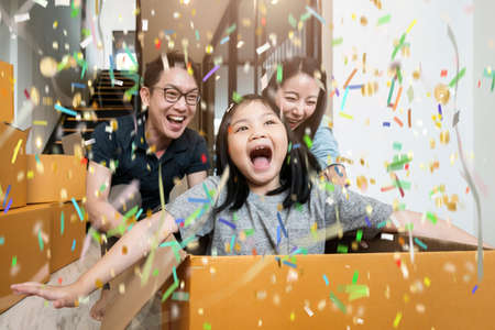happiness asian family mom dad daughter moving in new house hand carry box of stuff with exited and fun cheerful expressionの写真素材