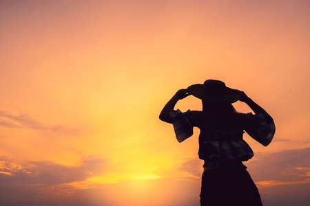 silhouette of asian teen woman hand rise hat to the sky on sunset beach freedom ideas concept