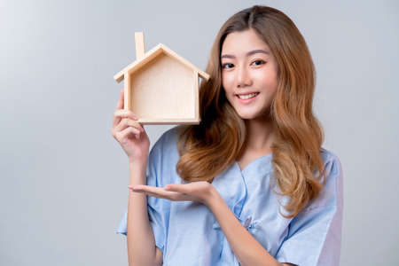 business healthy insurance beautiful asian female in hospital uniform smile with hand house model  ideas for happy insurance package and promotion with hospital blur backgroundの写真素材