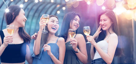 group of beautiful attractive asian friend female celebrating rooftop party together with cheerful drink dance mith rhythm party music with light flare and bokeh backgroundの写真素材