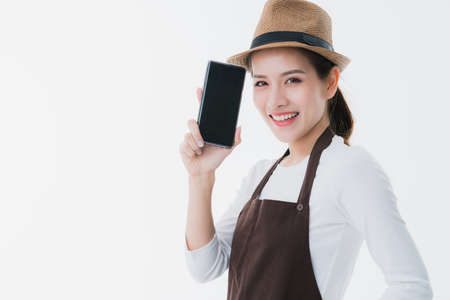 beautiful attractive asian shop owner with apron present black screen smartphone with happiness and joyful business startup ideas conceptの写真素材