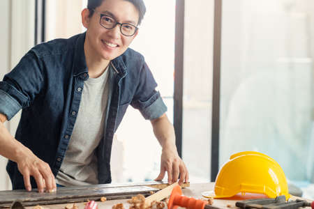 smart attractive handy glasses asian male craftman or interior designer focus wood working at site constrution home interior design house renovation and improvement conceptの写真素材