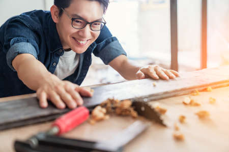 smart attractive handy glasses asian male craftman or interior designer focus wood working at site constrution home interior design house renovation and improvement conceptの写真素材