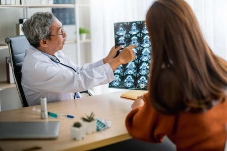 asian expert doctor examine and explain x-ray film to patient with care and happiness health ideas conceptの写真素材